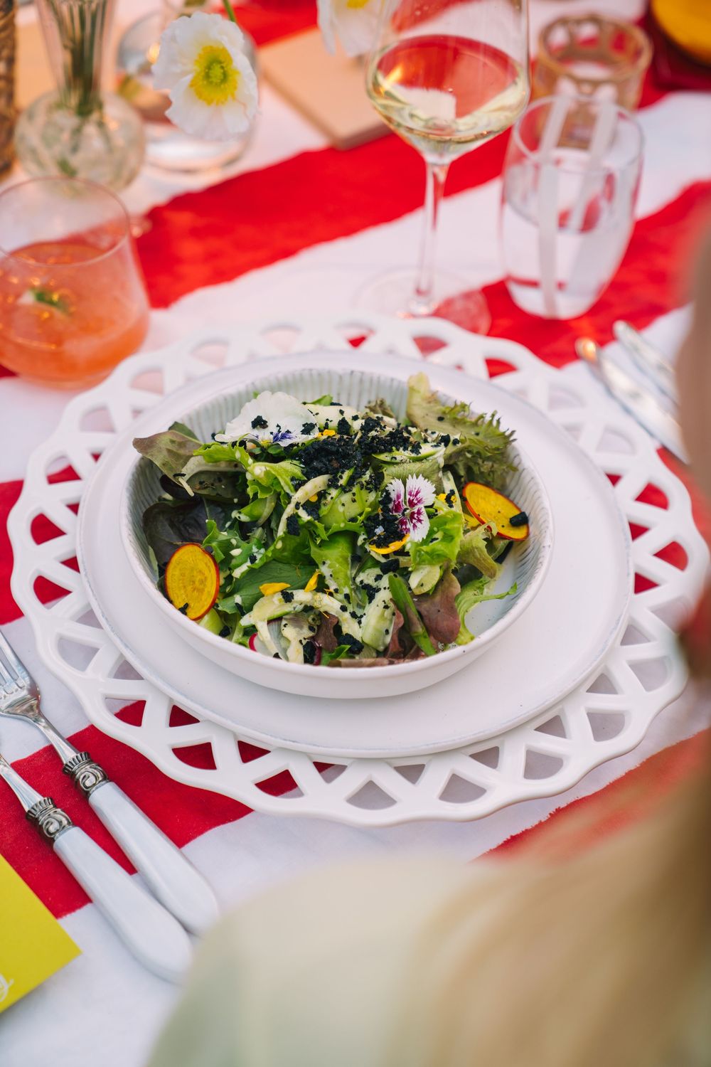 Fresh garden salad served on white decorative plate with red table setting.