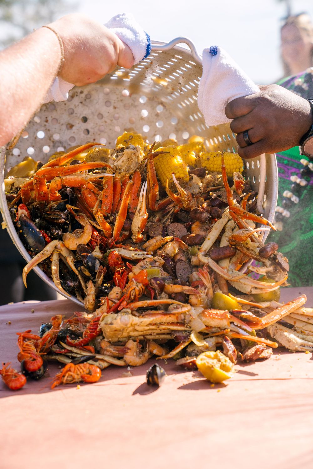 Seafood boil being dumped onto table with corn, crab, and crawfish.