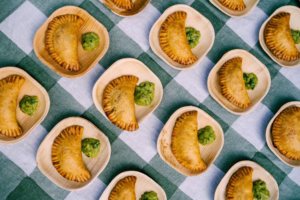Rows of golden baked mini pies garnished with herbs on a checkered surface.