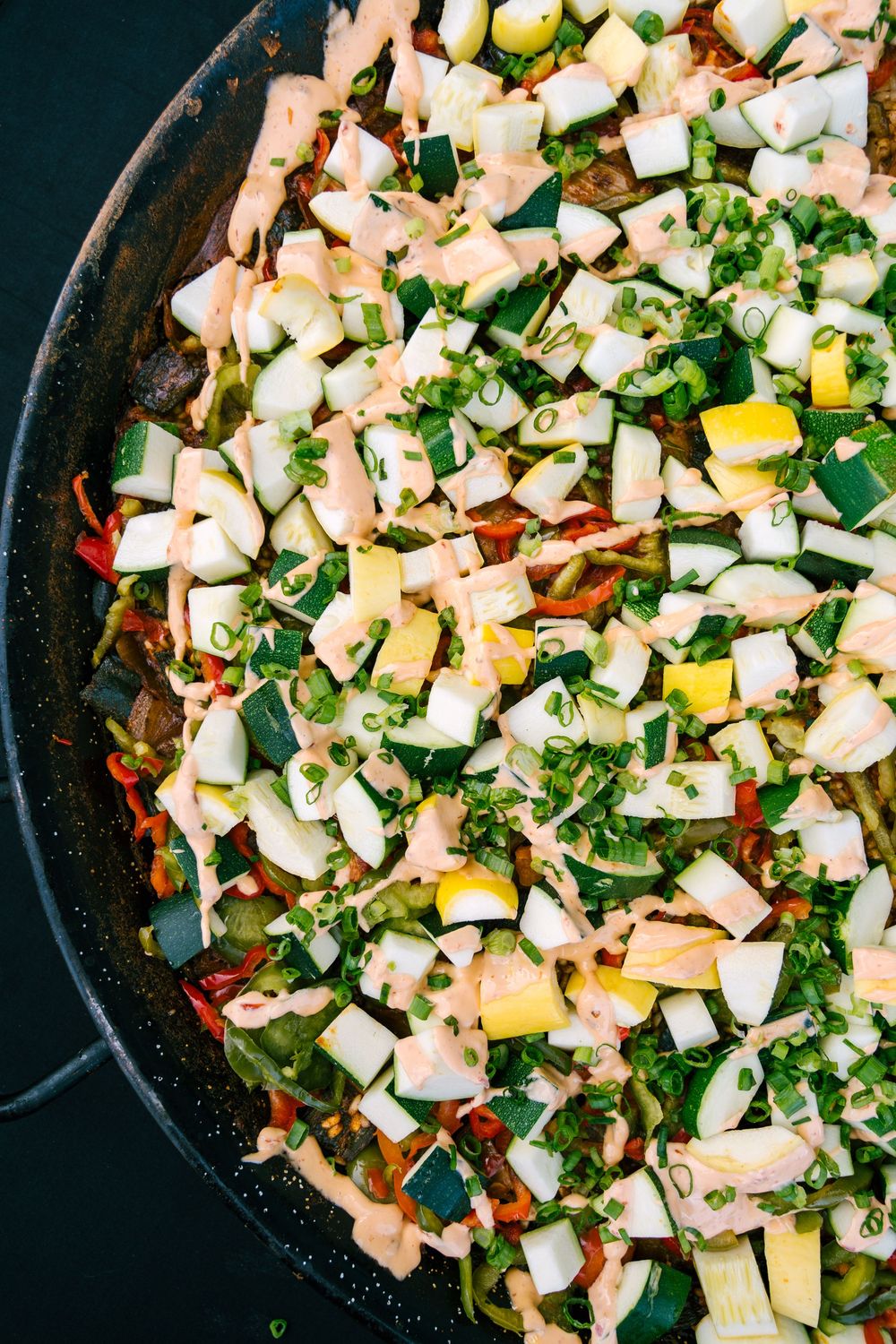 Overhead shot of a skillet filled with colorful diced vegetables and herbs.