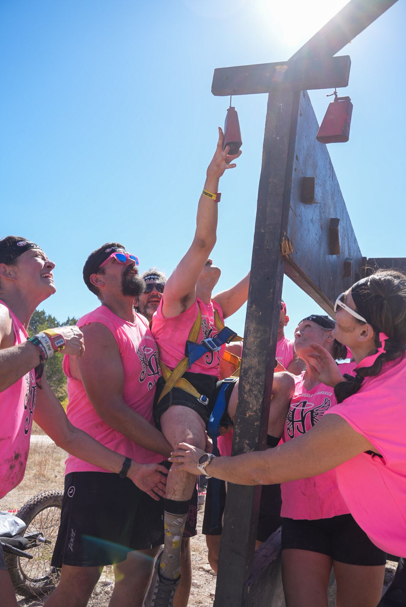 Spartan Race participants helping a disabled person finish an obstacle, showcasing teamwork and support.
