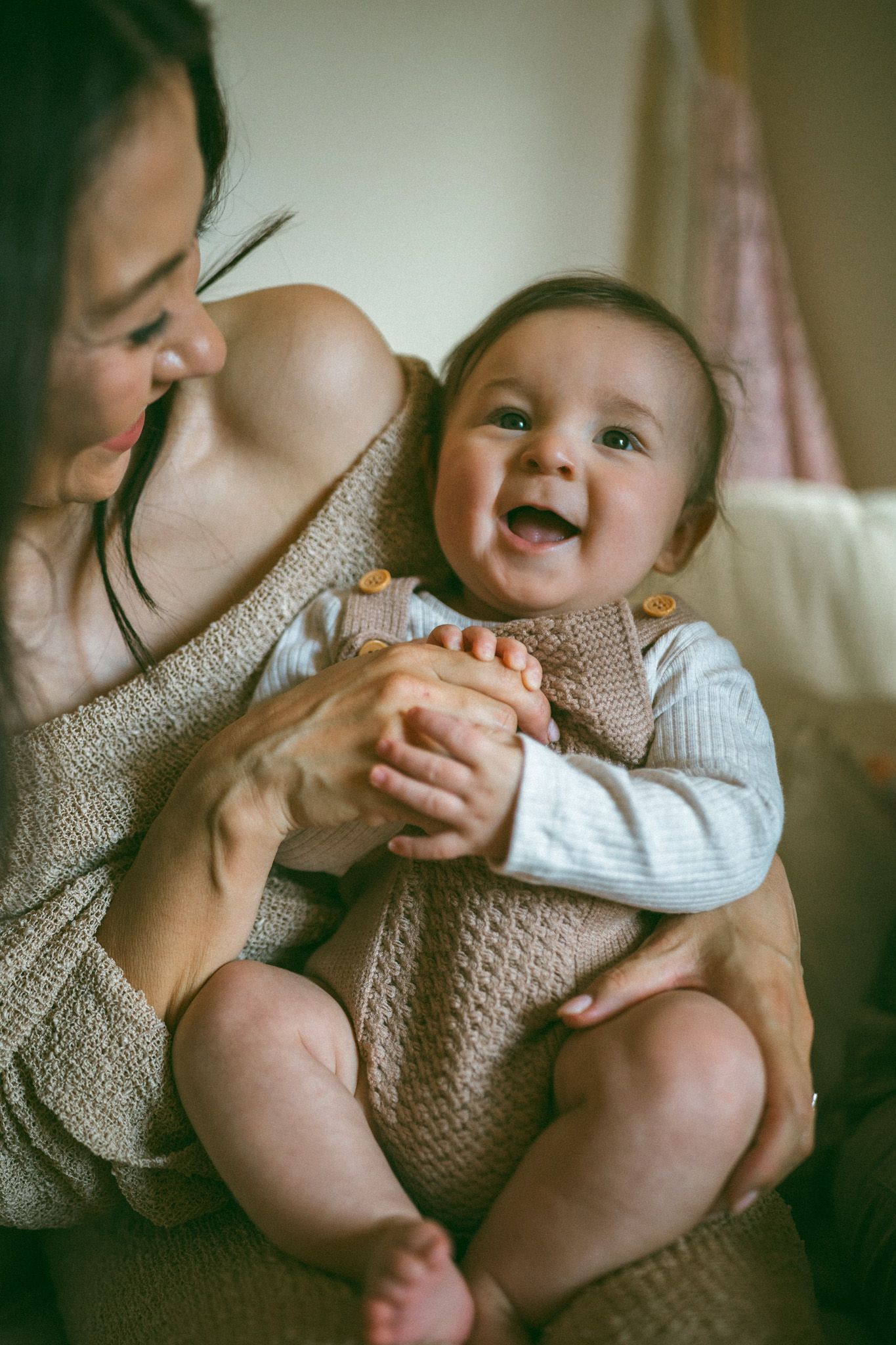 A tender moment as a newborn baby wrapped in a brown knit blanket is gently cradled in loving arms.
