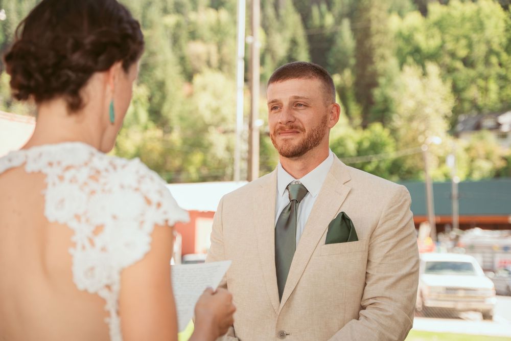 Wedding couple shares a romantic moment outdoors surrounded by greenery and sunlight.
