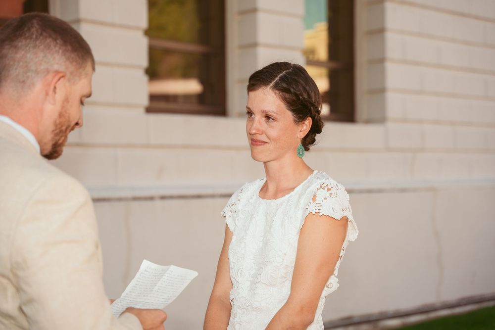 Wedding couple shares intimate moment in elegant white dress and beige suit.
