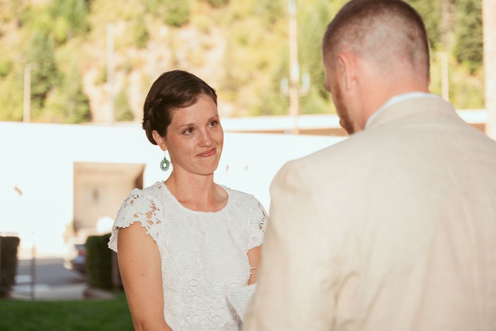 Two people share an intimate moment during a wedding ceremony outdoors.