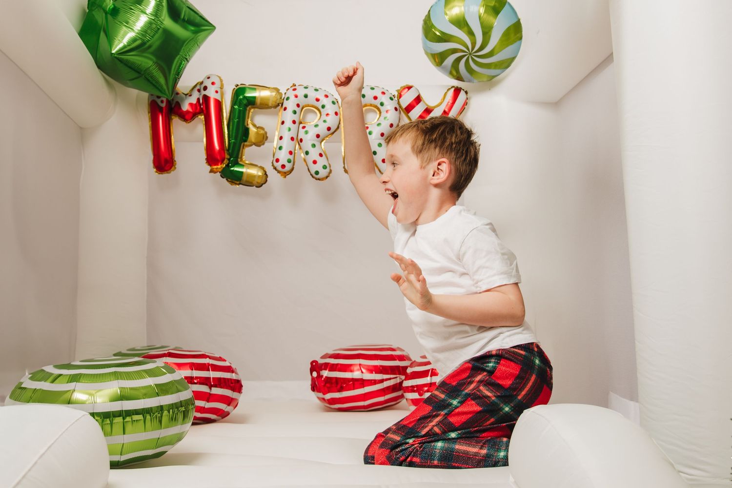 Whimsical Christmas photo setup with green and red balloon decorations against white backdrop.