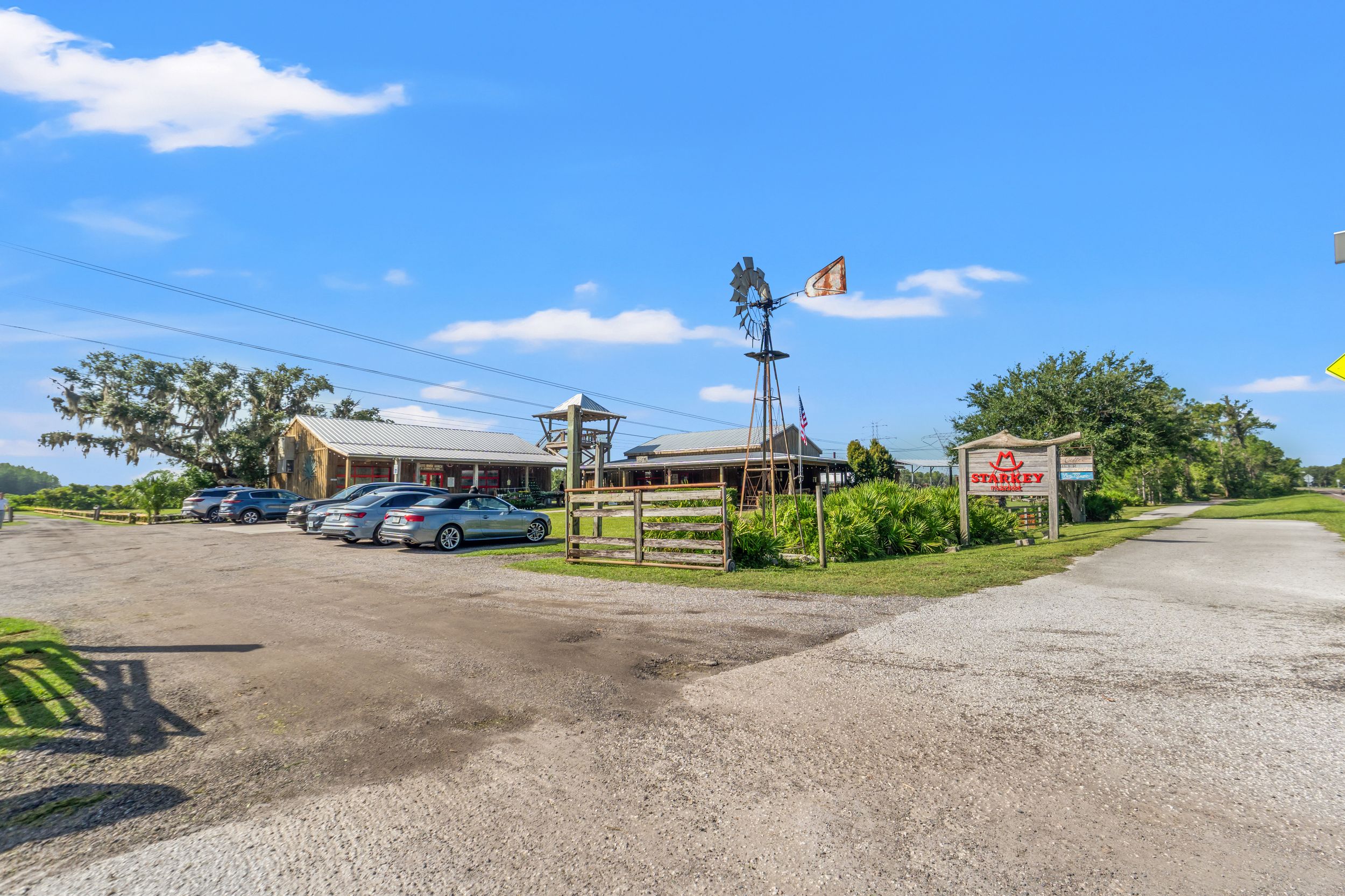 Panoramic view of rural buildings and parking area under blue sky.