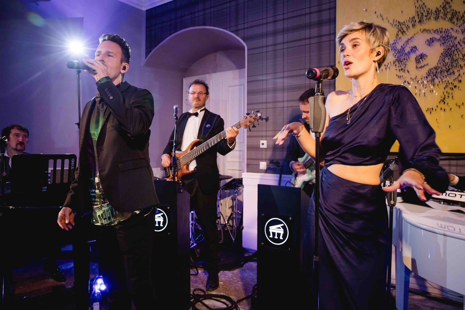 Musicians perform on stage in navy blue outfits with dramatic purple lighting during an elegant evening event.