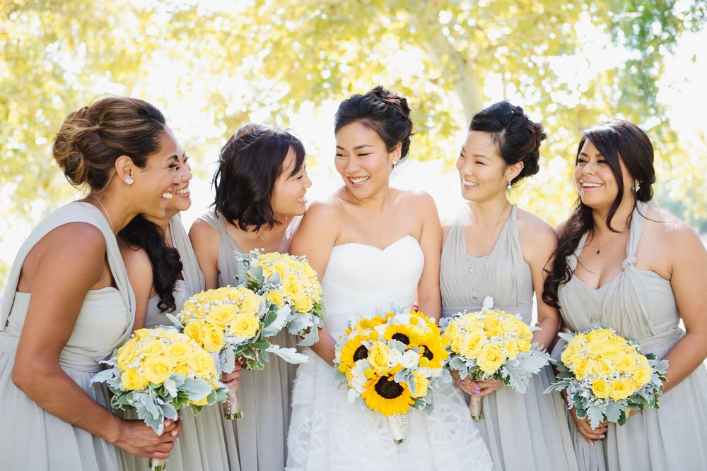 Wedding party lineup with bridesmaids in grey dresses holding yellow sunflower bouquets.