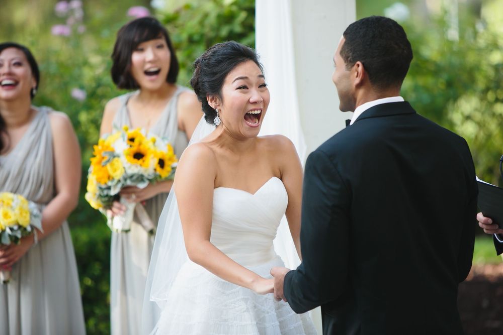 A joyful wedding ceremony moment captured under white drapes and sunflower decorations.