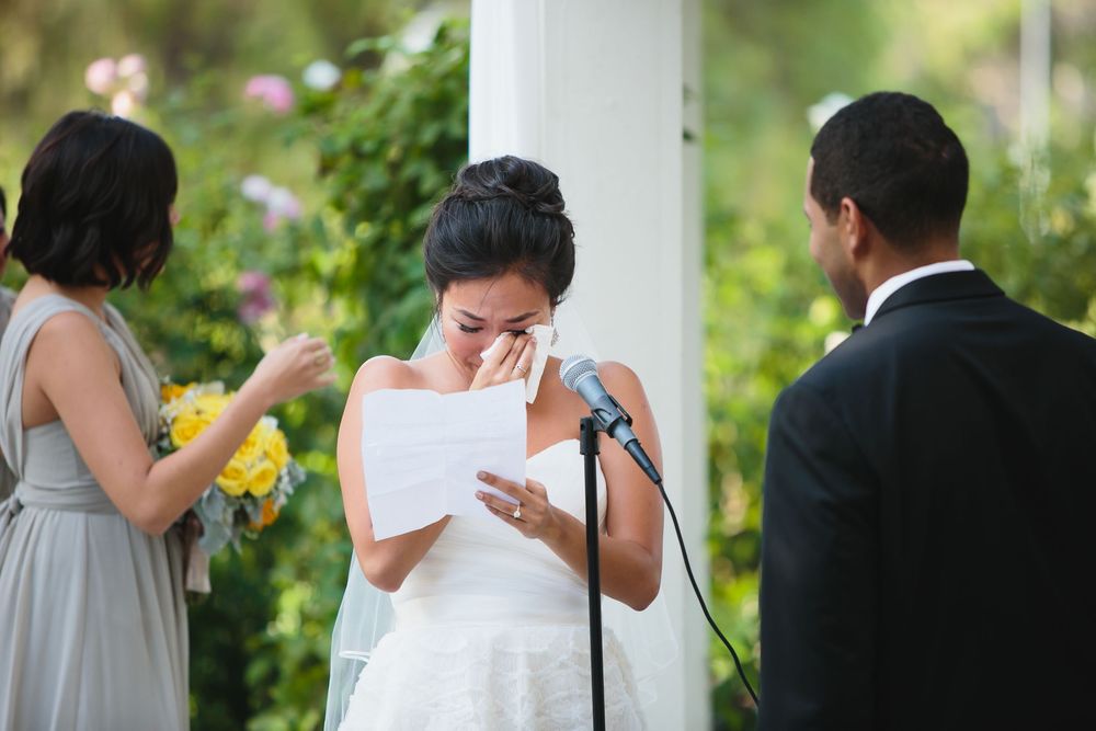 Emotional reactions during a wedding ceremony underneath a white draped gazebo.