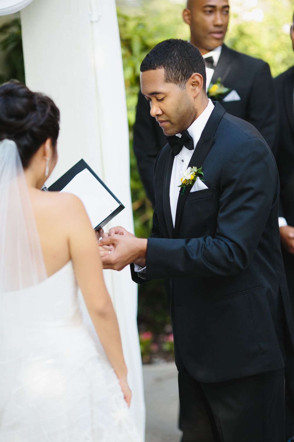 Ring exchange moment during an outdoor wedding ceremony with white decor.