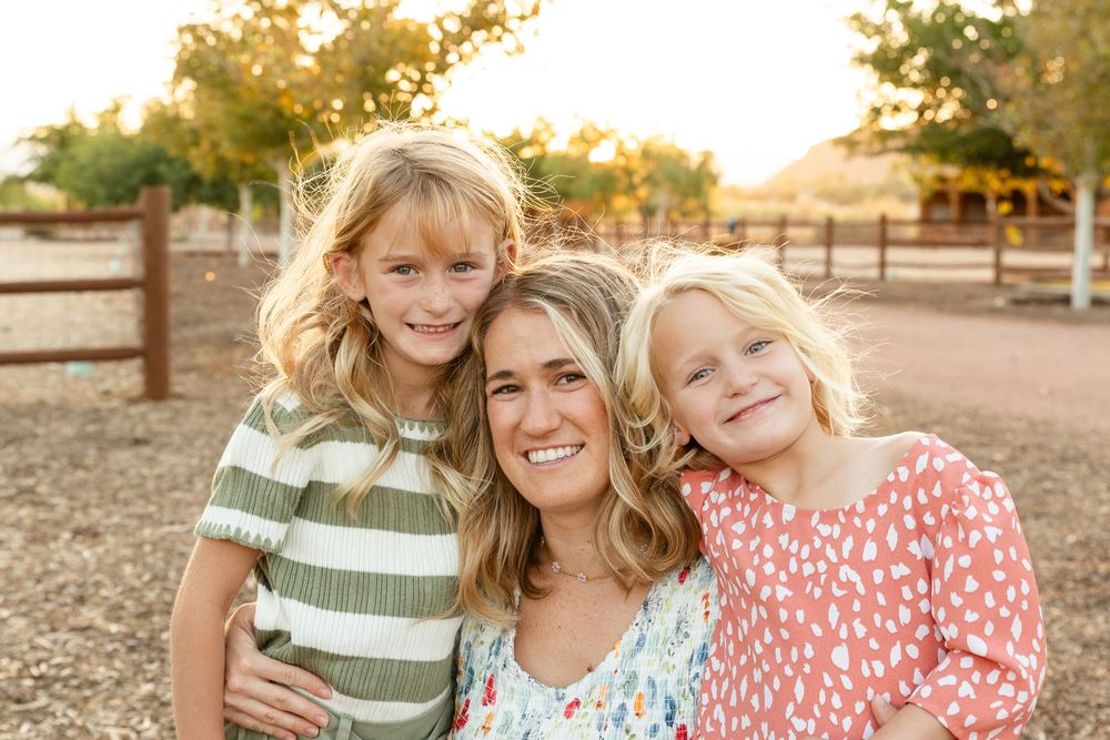 portrait of mom and a 5 and 8 year old daughter on either side smiling at the camera