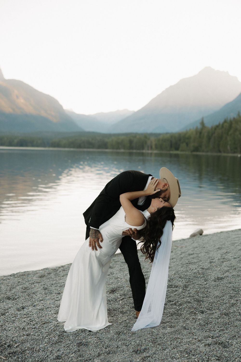 A playful wedding photo sequence showing a couple dipping and dancing by a scenic mountain lake.