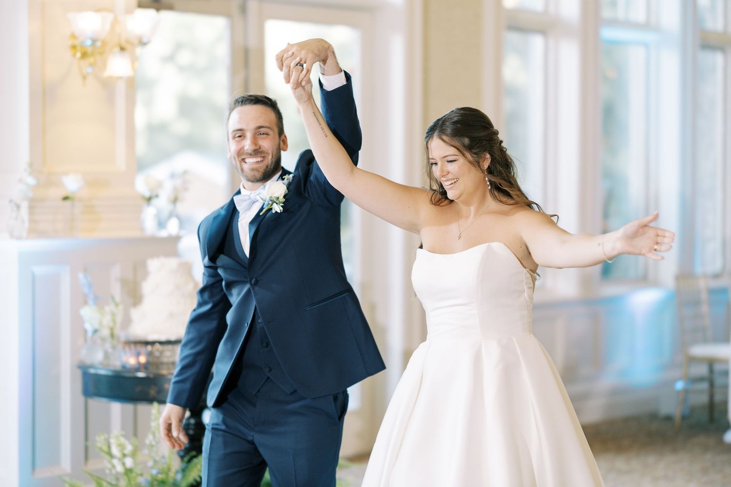 Joyful wedding celebration with couple and guests cheering and raising their hands in an elegant venue.