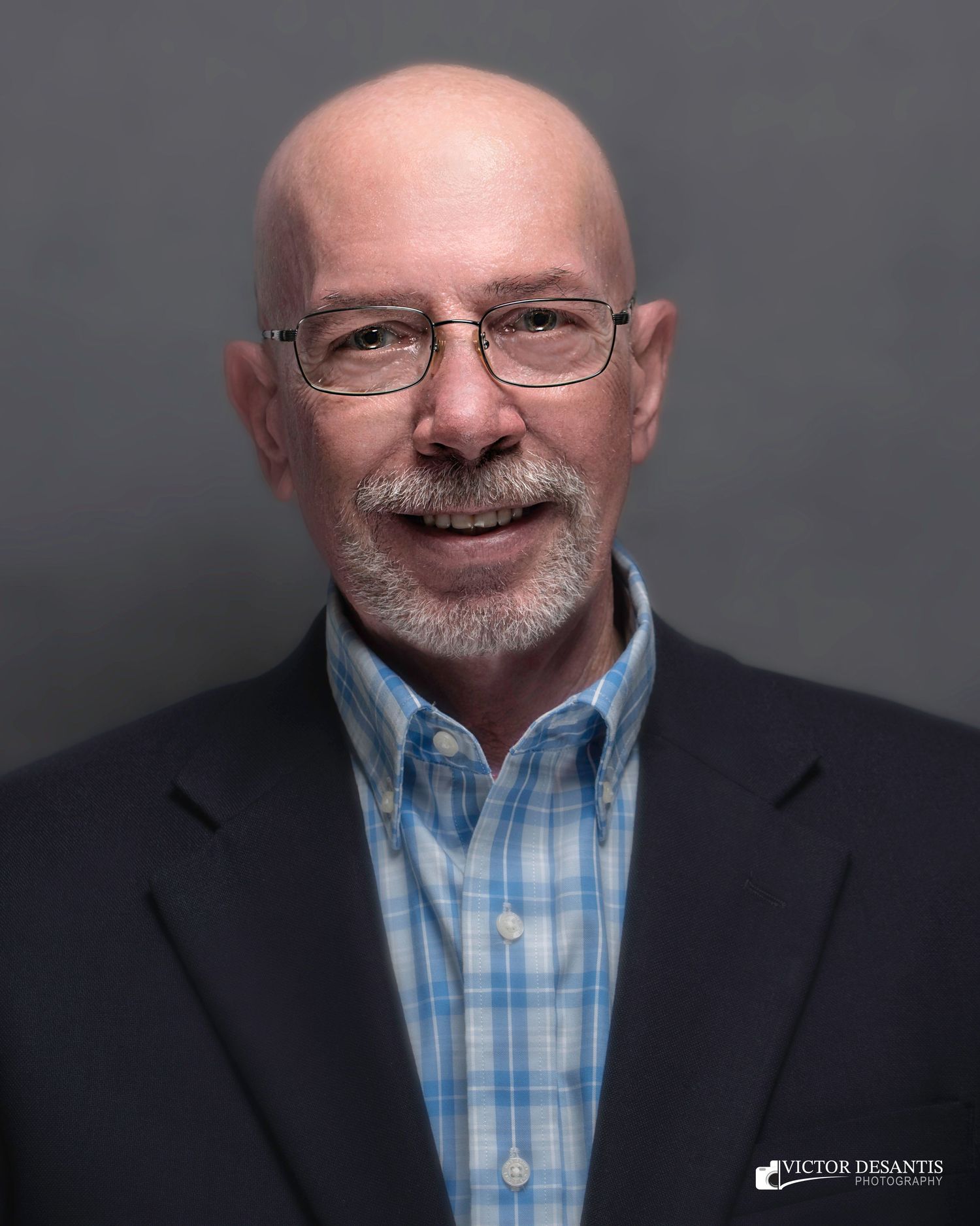 Professional headshot series showing navy suit and blue checkered shirt against dark gray backdrop.