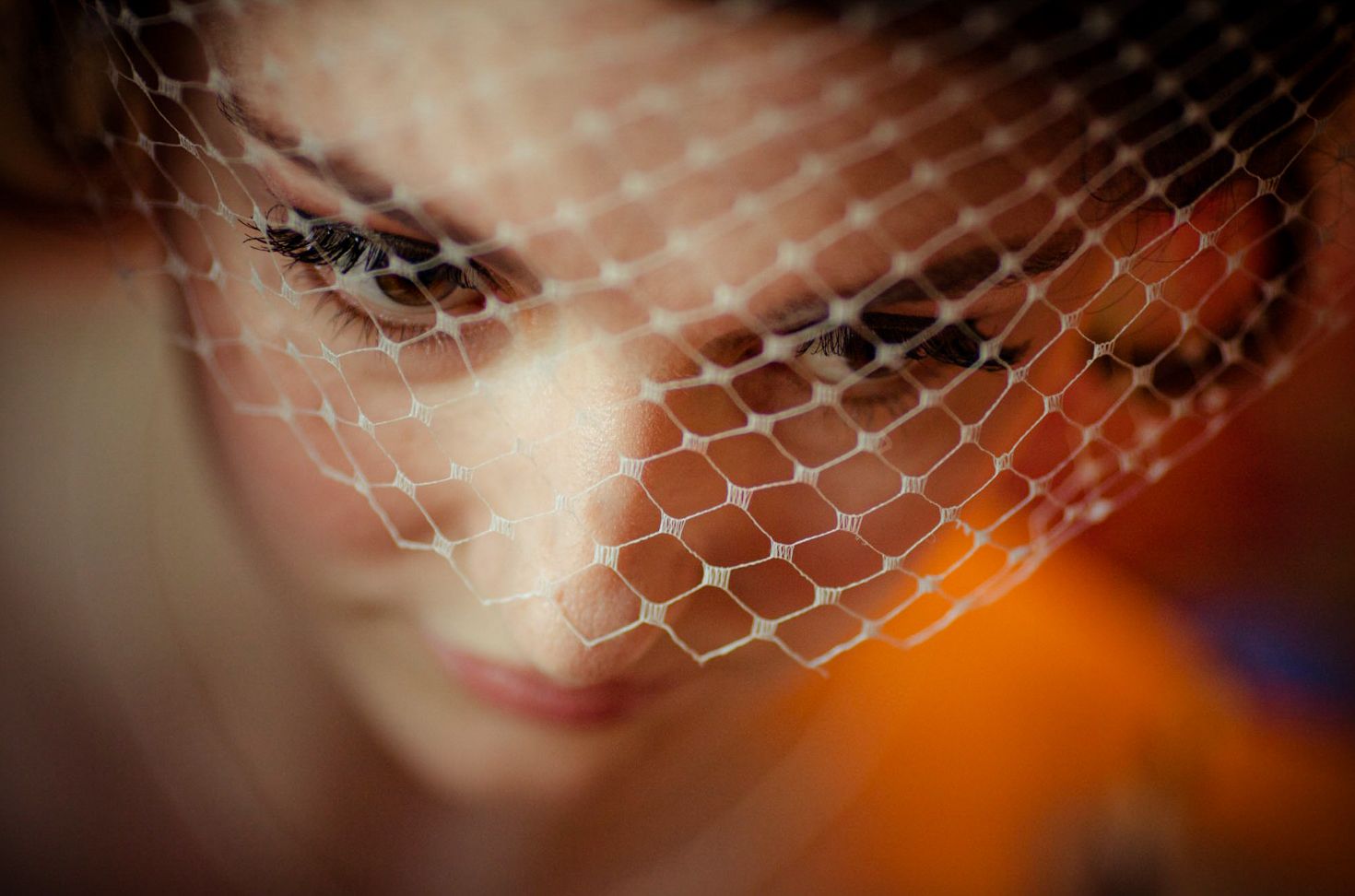 Close-up artistic shot of delicate bridal veil netting against warm background lighting.