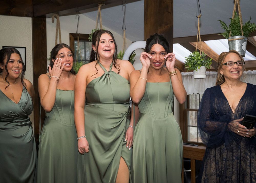 Bridesmaids in sage green dresses posing together during wedding preparations.