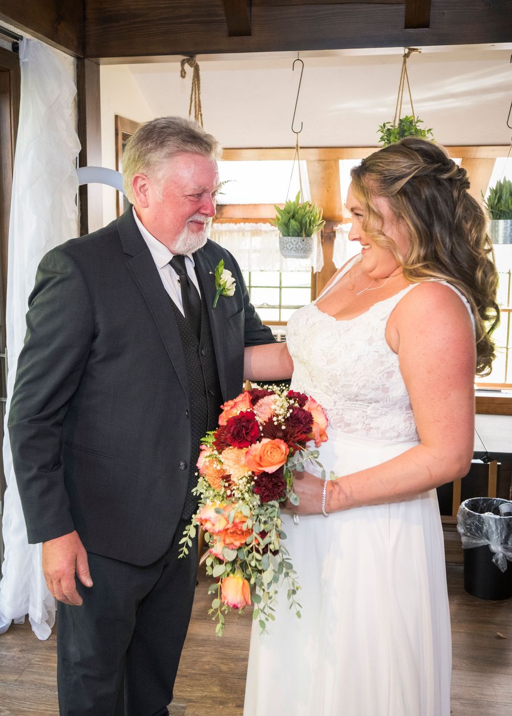 Wedding couple shares intimate moments in an indoor venue with rustic wooden beams and warm lighting.