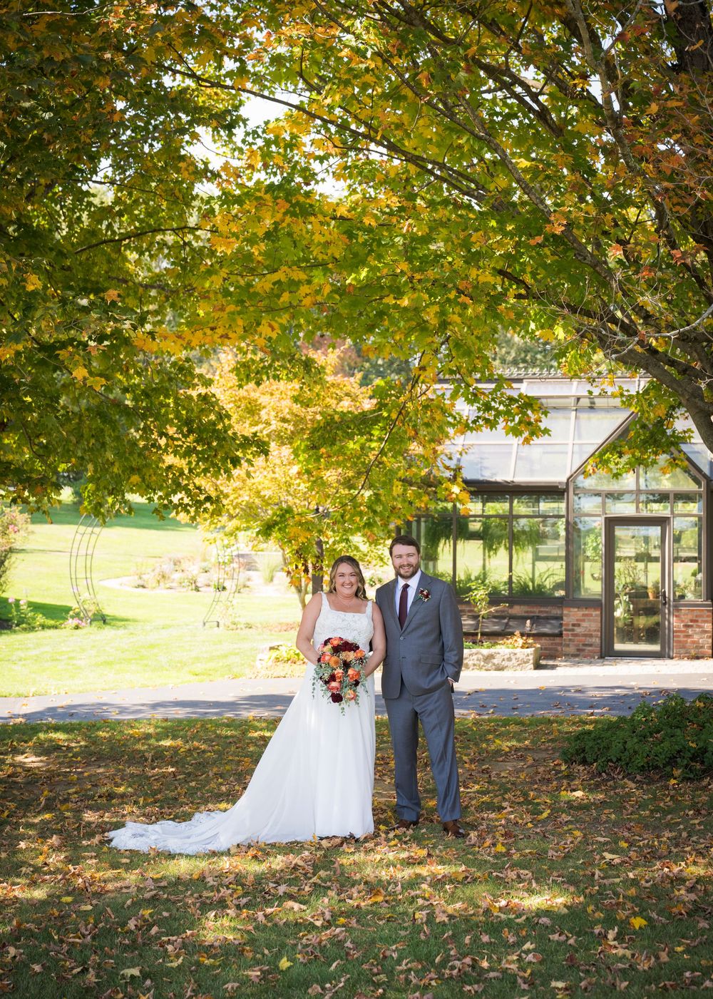 Wedding portraits taken in a scenic fall setting with golden leaves and stone pillars.