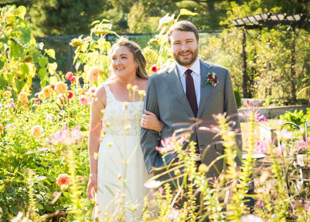 Wedding party photos taken in a sunlit garden with colorful flowers.