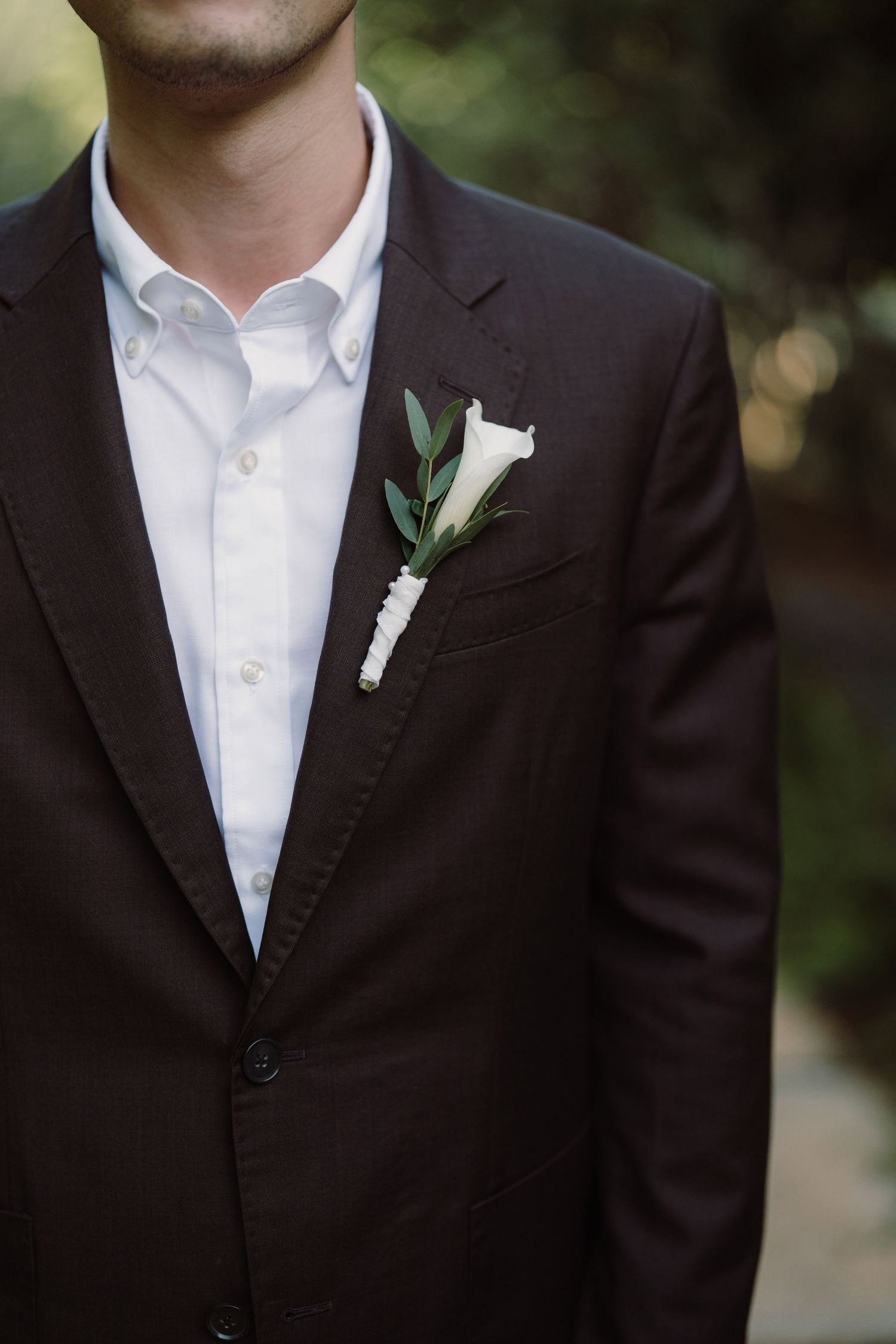 Close-up detail of a formal black suit jacket with white boutonniere.