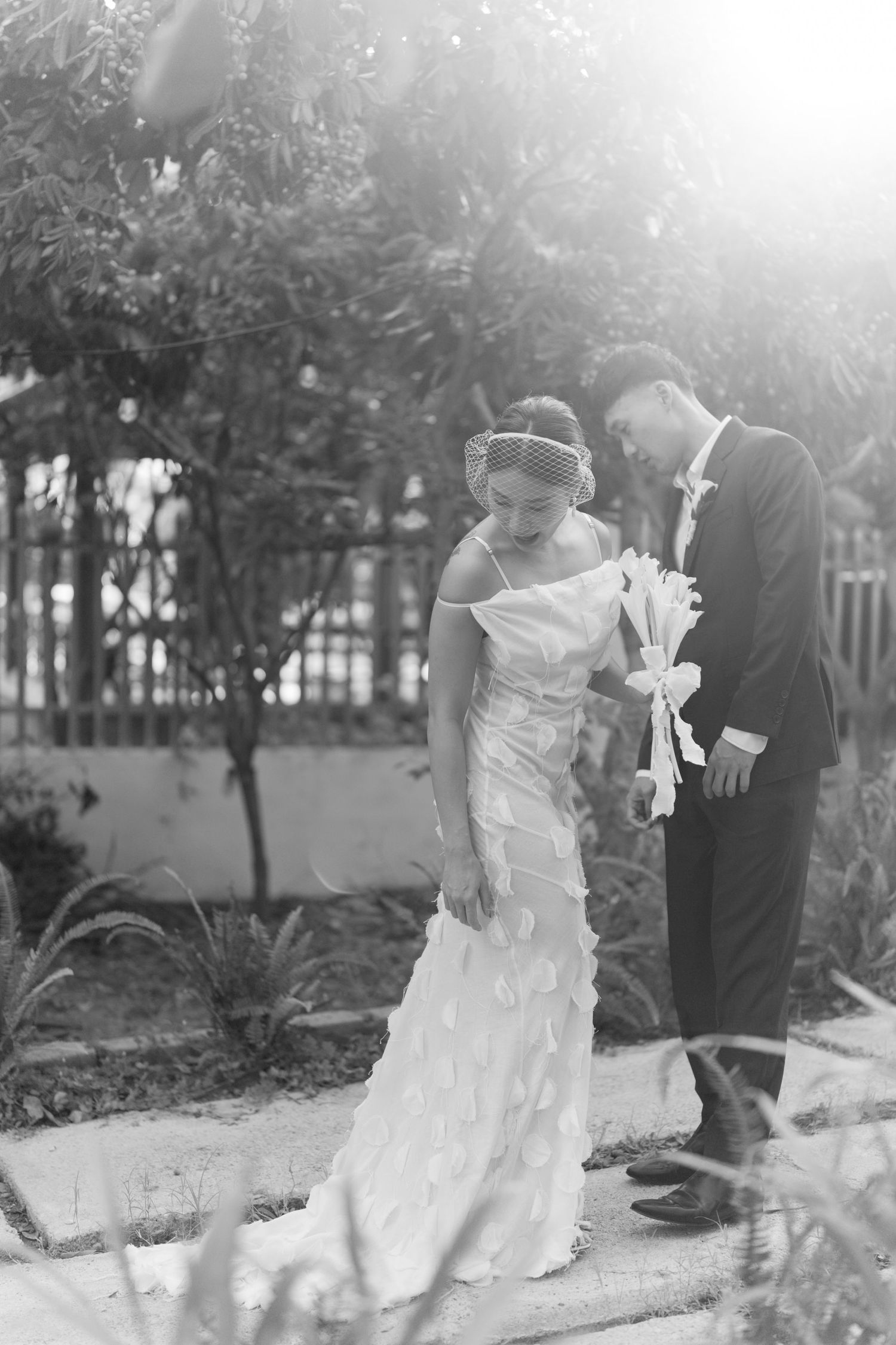 A romantic black and white photo of a couple in formal attire in a garden setting.