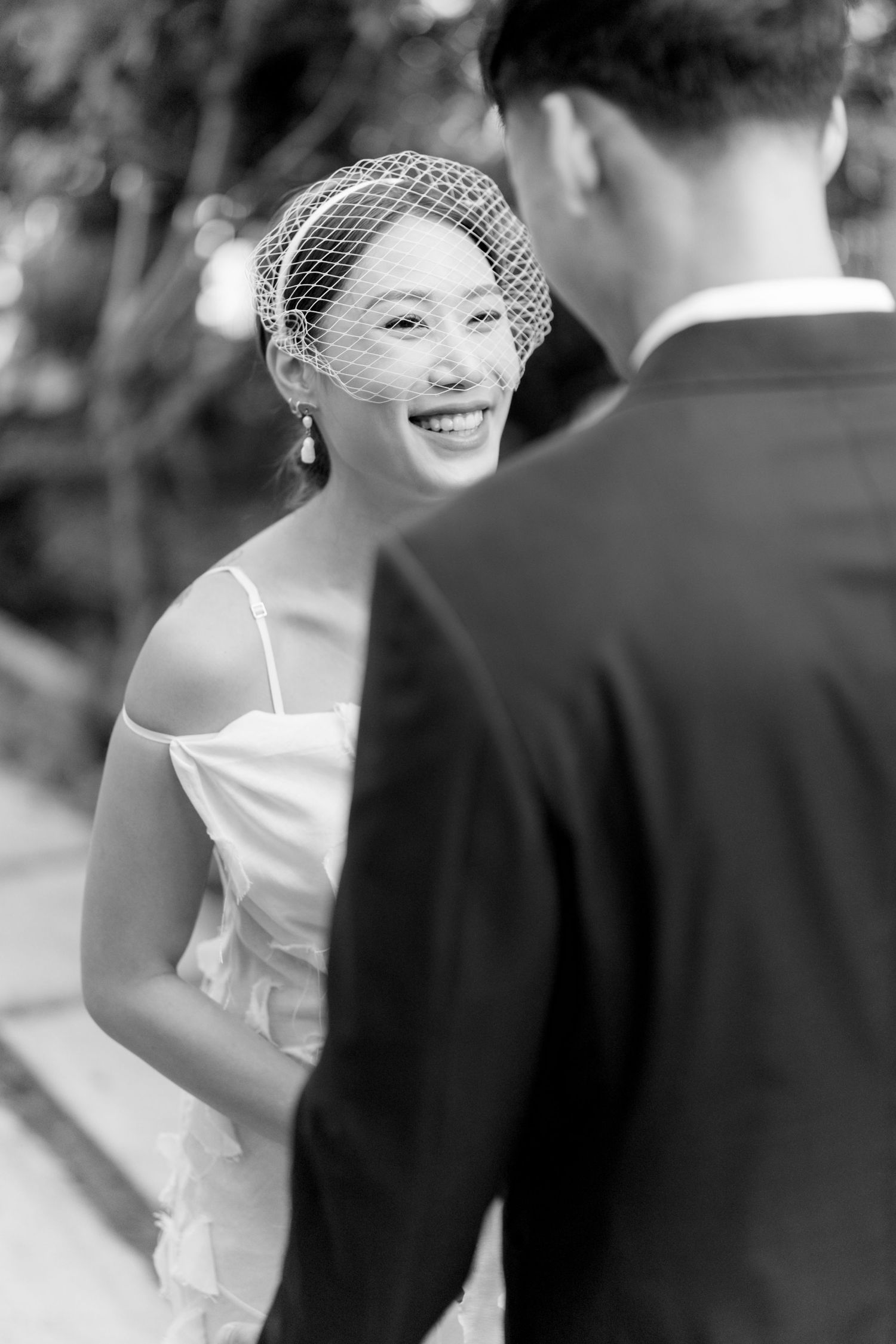 Black and white portrait capturing a joyful moment with vintage-style wedding accessories.