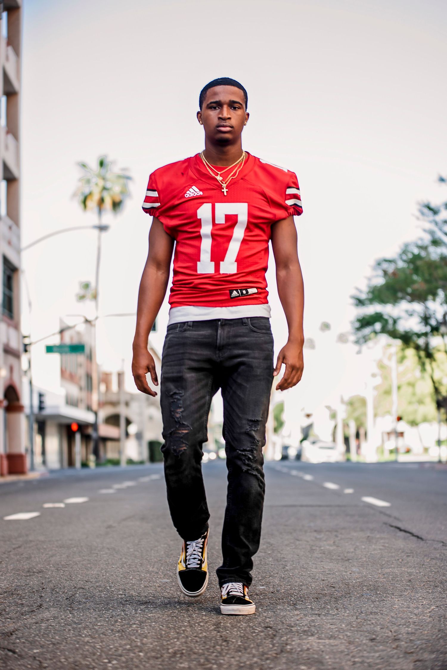 Athletic portrait series showing footwork and movement on city street in red sports jersey.