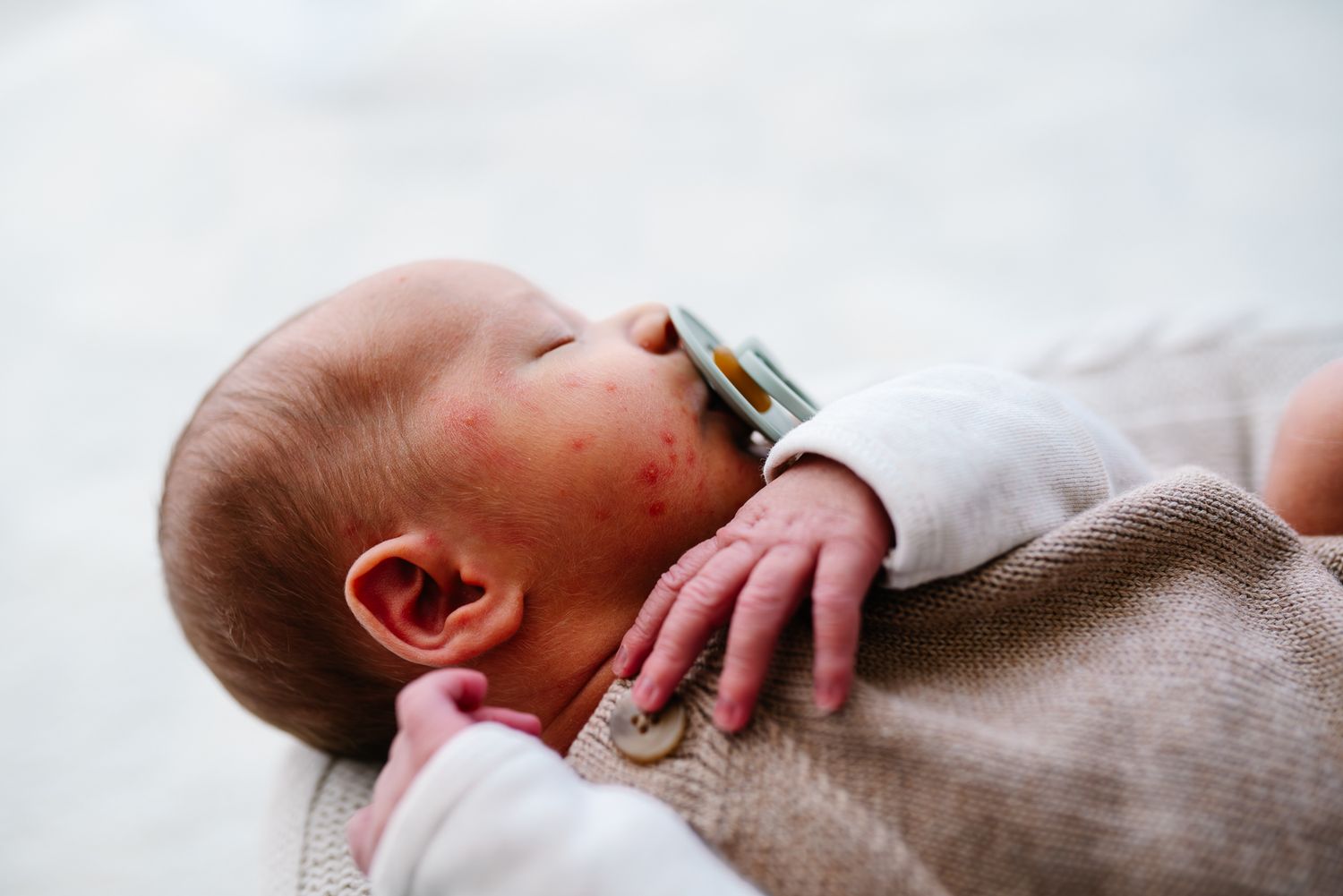 A sleeping newborn baby sleeps while wearing a soft beige bodysuit taken during an in home newborn photography session in Melbourne.