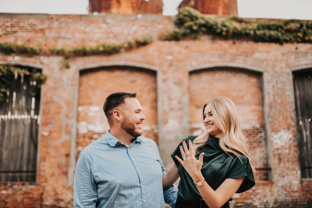 Golden hour engagement proposal with rustic brick backdrop at Cotton Mill