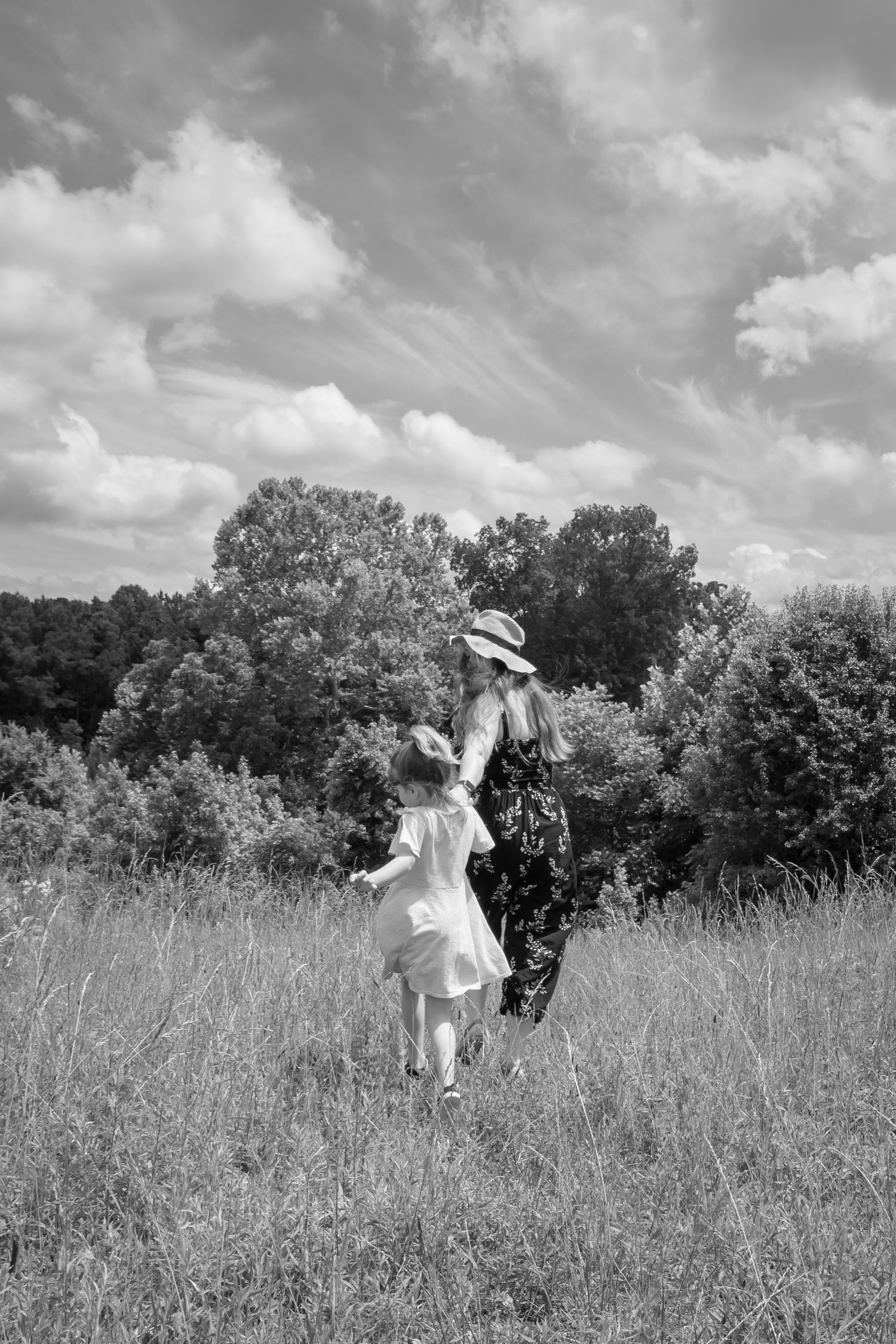Children playing in a tall grass meadow on a summer day with dramatic cloudy skies.