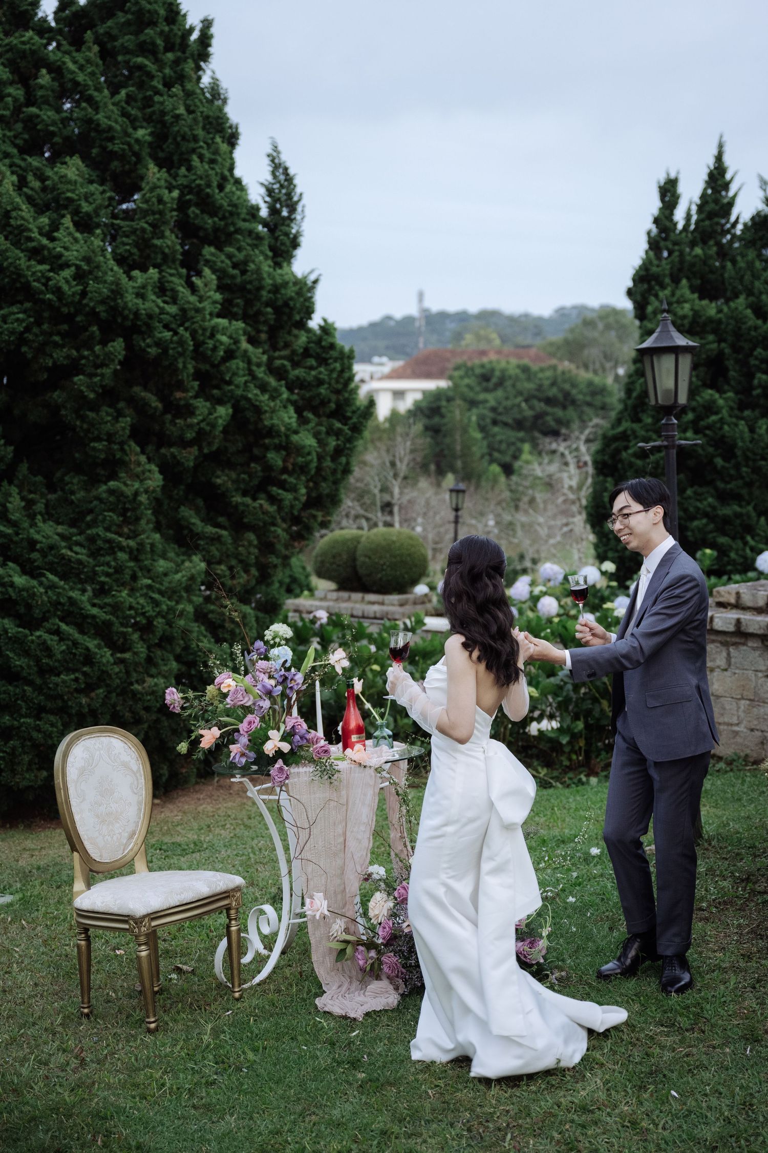 Bride and groom exchange rings beside a decorative floral cart in a beautifully landscaped garden.