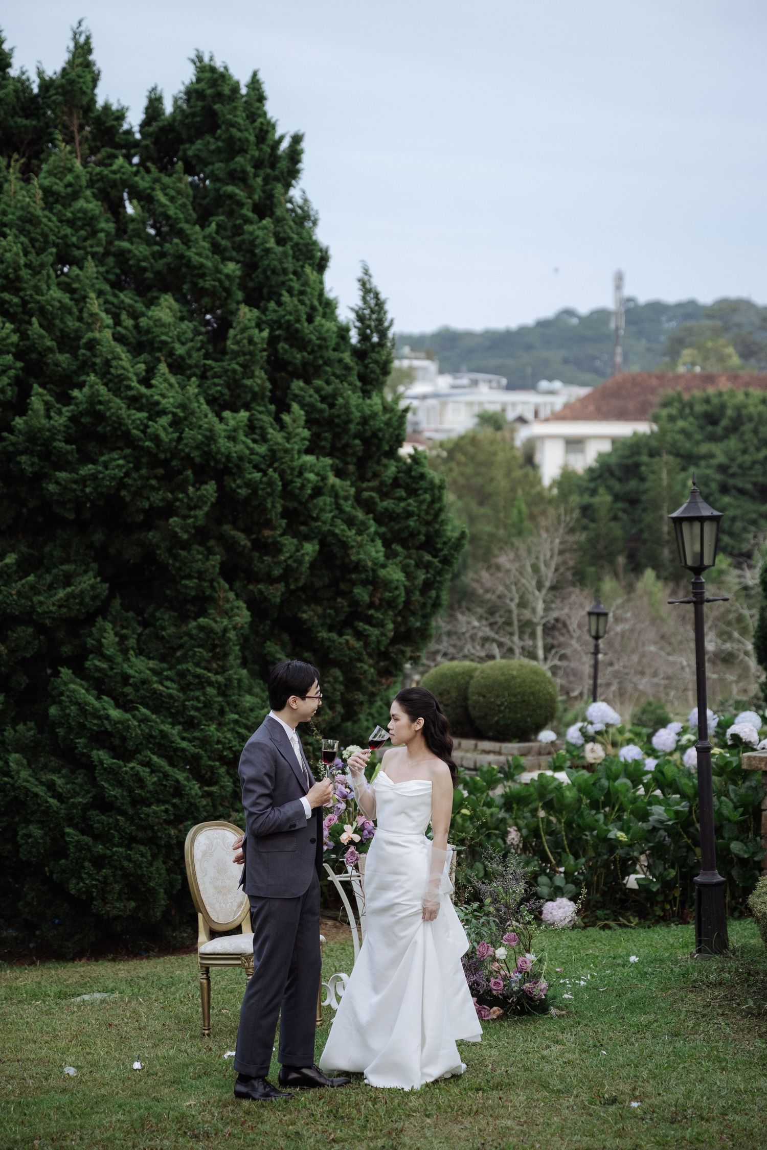 Bride and groom share a romantic moment in a lush garden, bride holding a bouquet in a white gown.