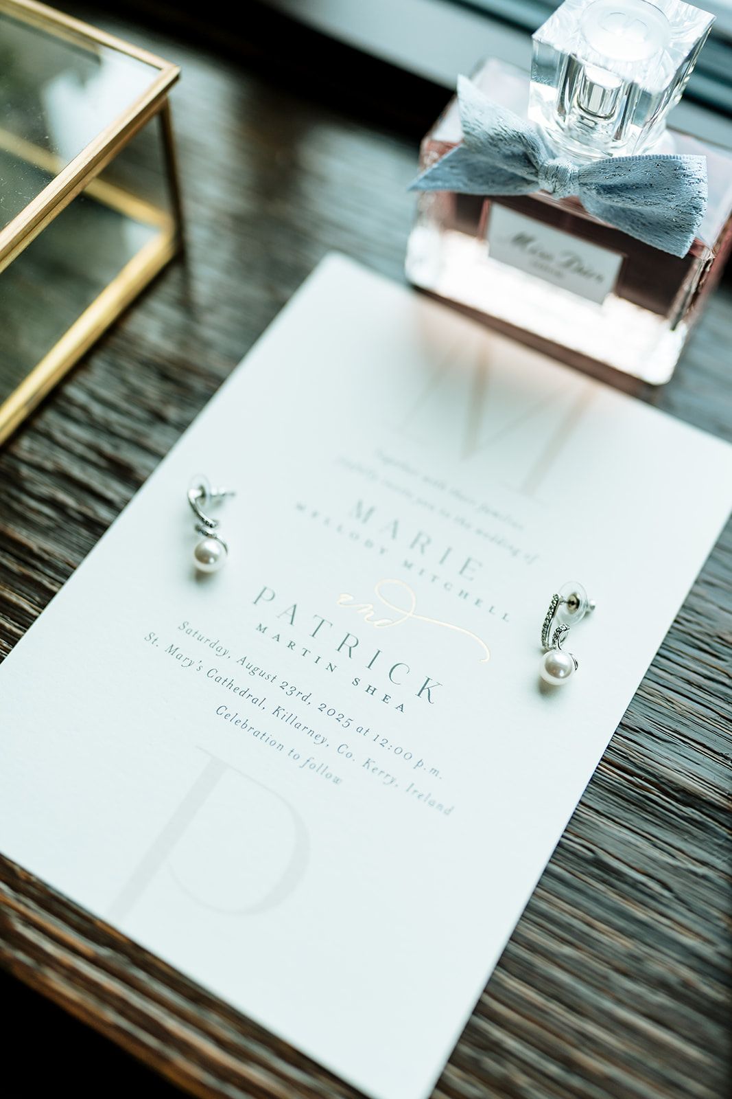 White paper invitations and place cards arranged in a sequence showing wedding stationery details on a rustic wooden table.