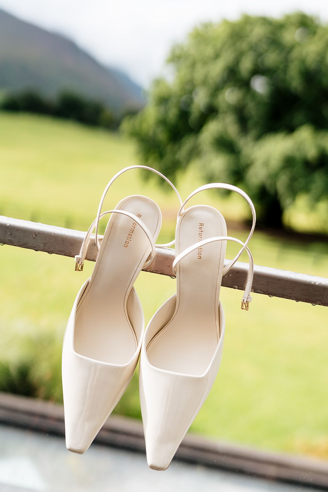 Elegant white square-toe mules arranged in multiple overlapping poses against a blurred natural outdoor background.