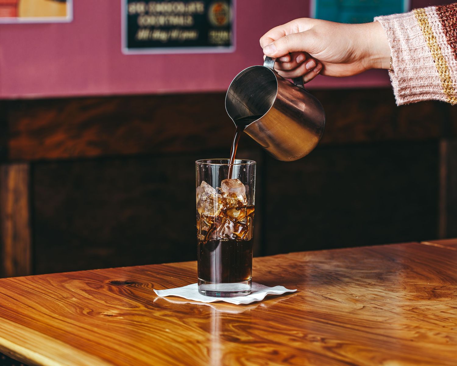 Beer being poured into a glass on a wooden table across multiple photos in a time-lapse sequence.