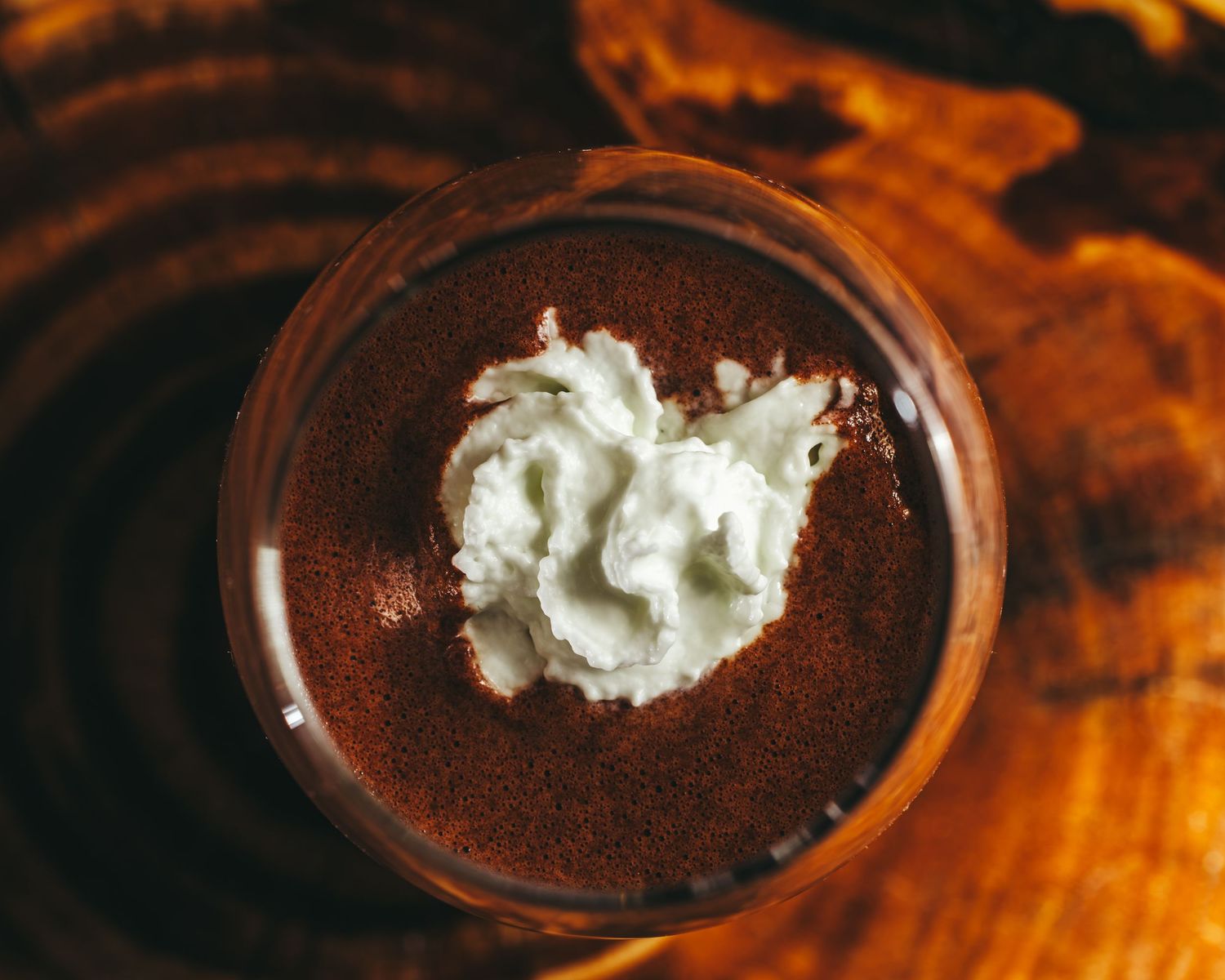 Rich chocolate mousse topped with fresh whipped cream served in elegant dark glass dessert cups.