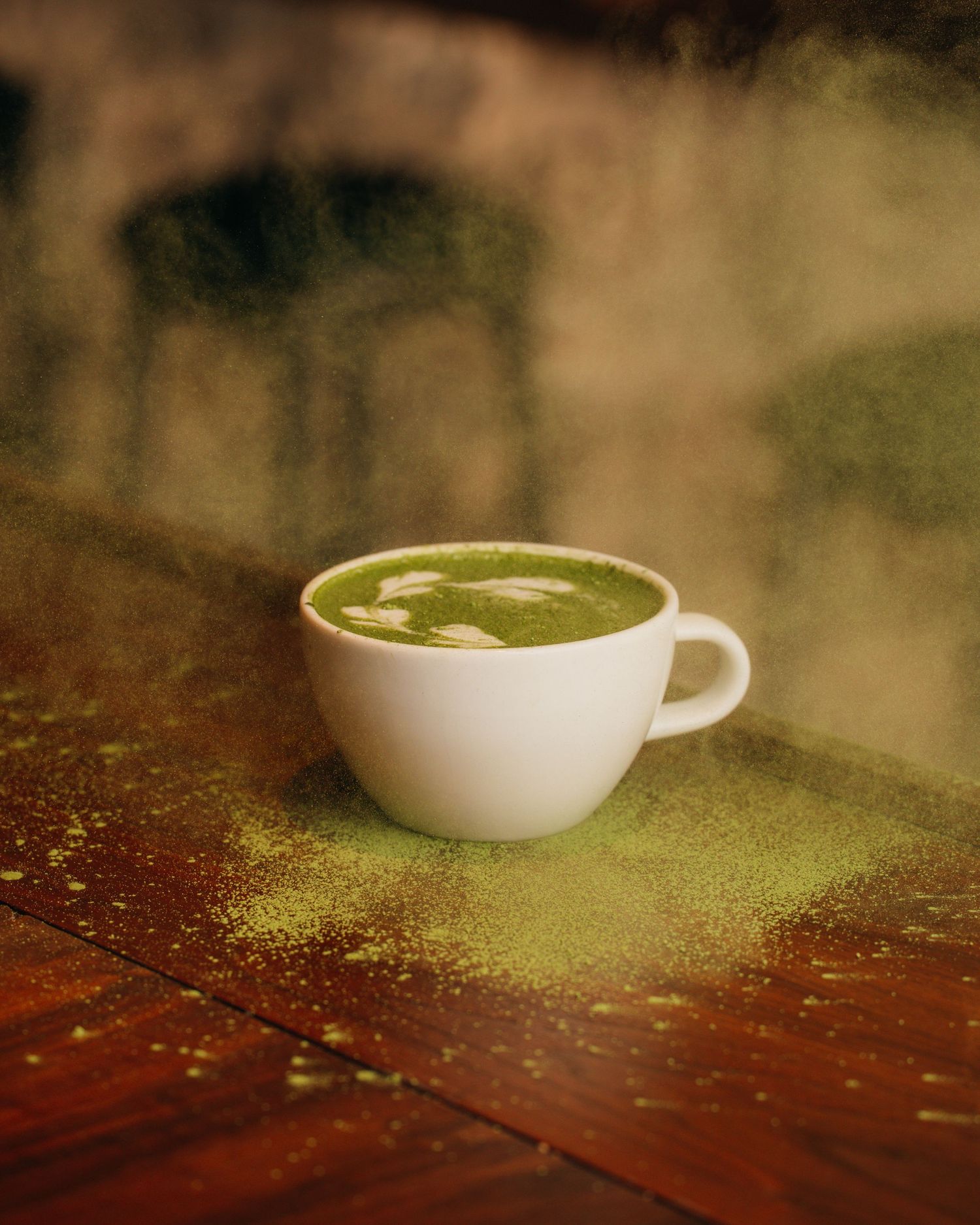A white coffee cup with latte art sits on a rustic wooden table with a soft, atmospheric lighting effect.