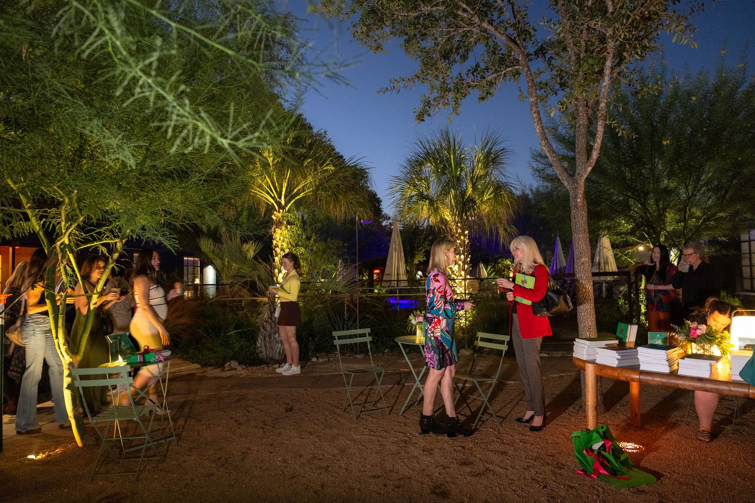 Outdoor event space at dusk with string lights creating a warm ambiance among trees.