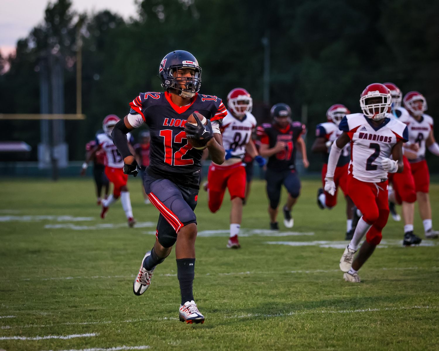 Football players in red and blue uniforms engage in a play on a grass field during a game.