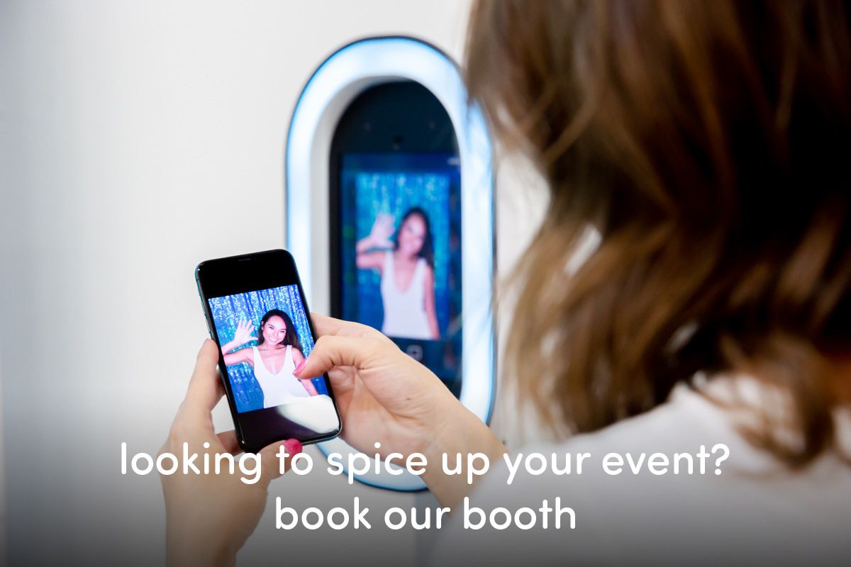 Person interacting with a photo booth at an event as neon lights glow in the background.