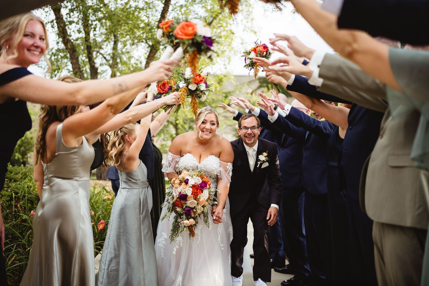 Wedding party celebrates with colorful autumn flower petals in outdoor garden setting.