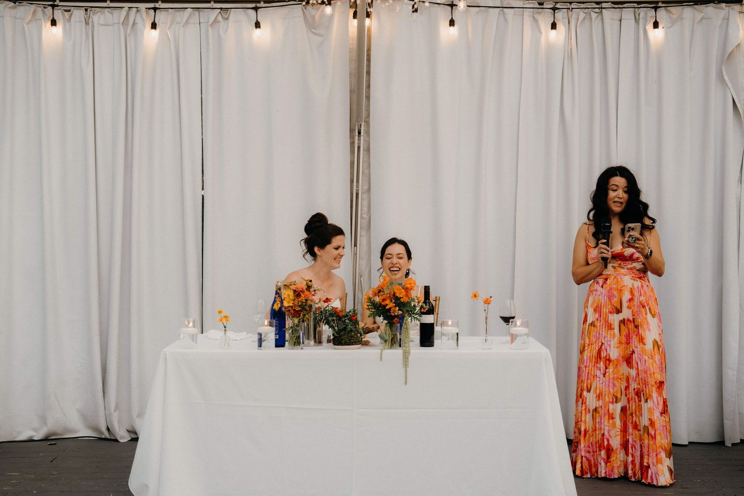 String lights hang above a white curtain backdrop in a wedding venue at the Sanctuary Roosevelt Island NYC