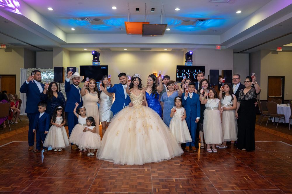 Panoramic view of a wedding reception with guests dancing in a ballroom under blue lighting.