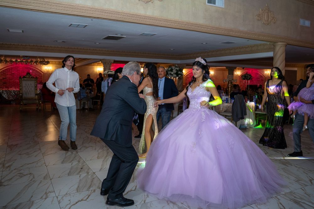 Couples dancing together in a formal ballroom setting with colorful decorative lighting and elegant attire.