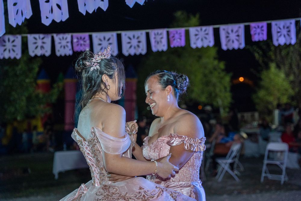 Guests dancing at a festive outdoor celebration with decorative papel picado banners hanging overhead.