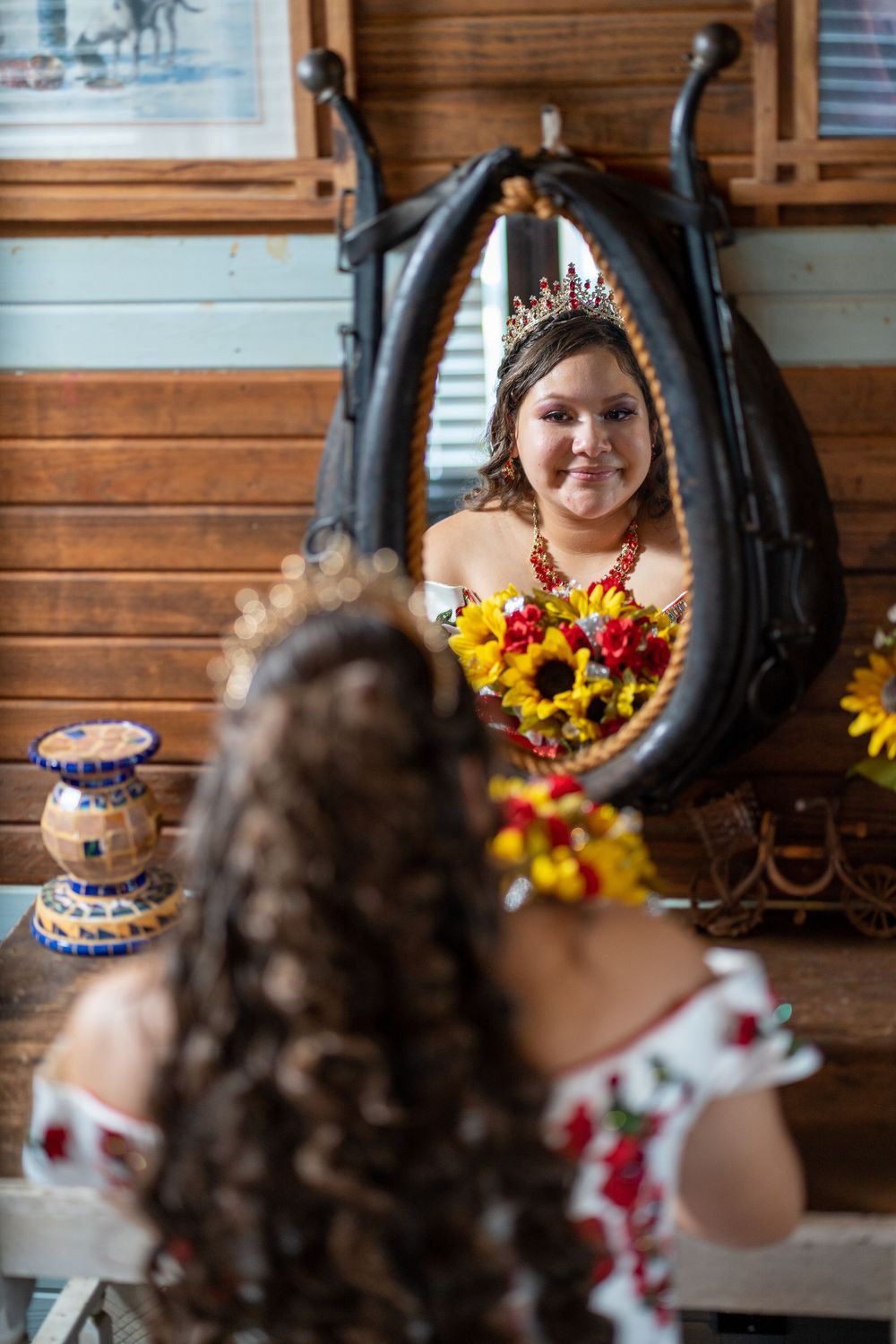 Ornate tiara and floral decorations reflected in a rustic mirror with wooden paneled walls.