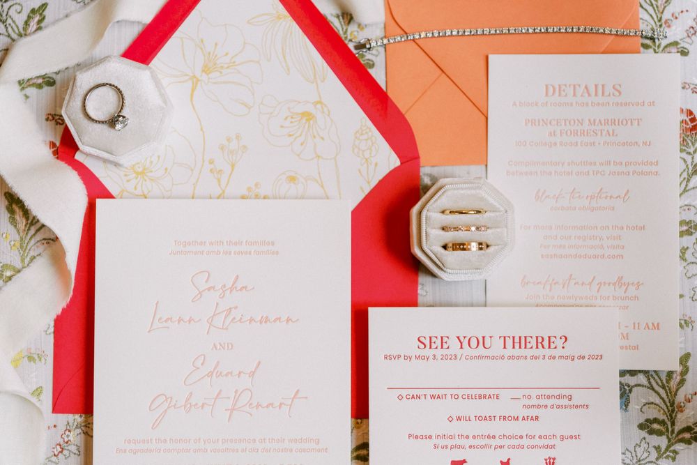 Elegant wedding invitation suite with coral and gold details on a white marble background.