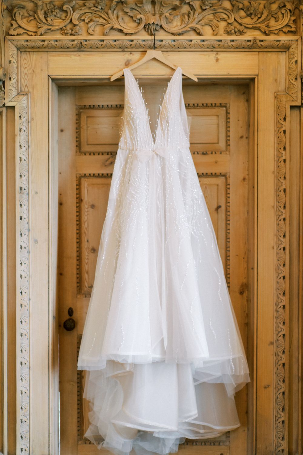 Multiple white tulle wedding dresses hanging on ornate gold-framed mirrors in an elegant dressing room.